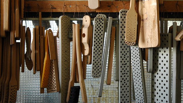 In der Werkstatt: Holzrohlinge in verschiedenen Formen und Größen hängen an einem Regal.